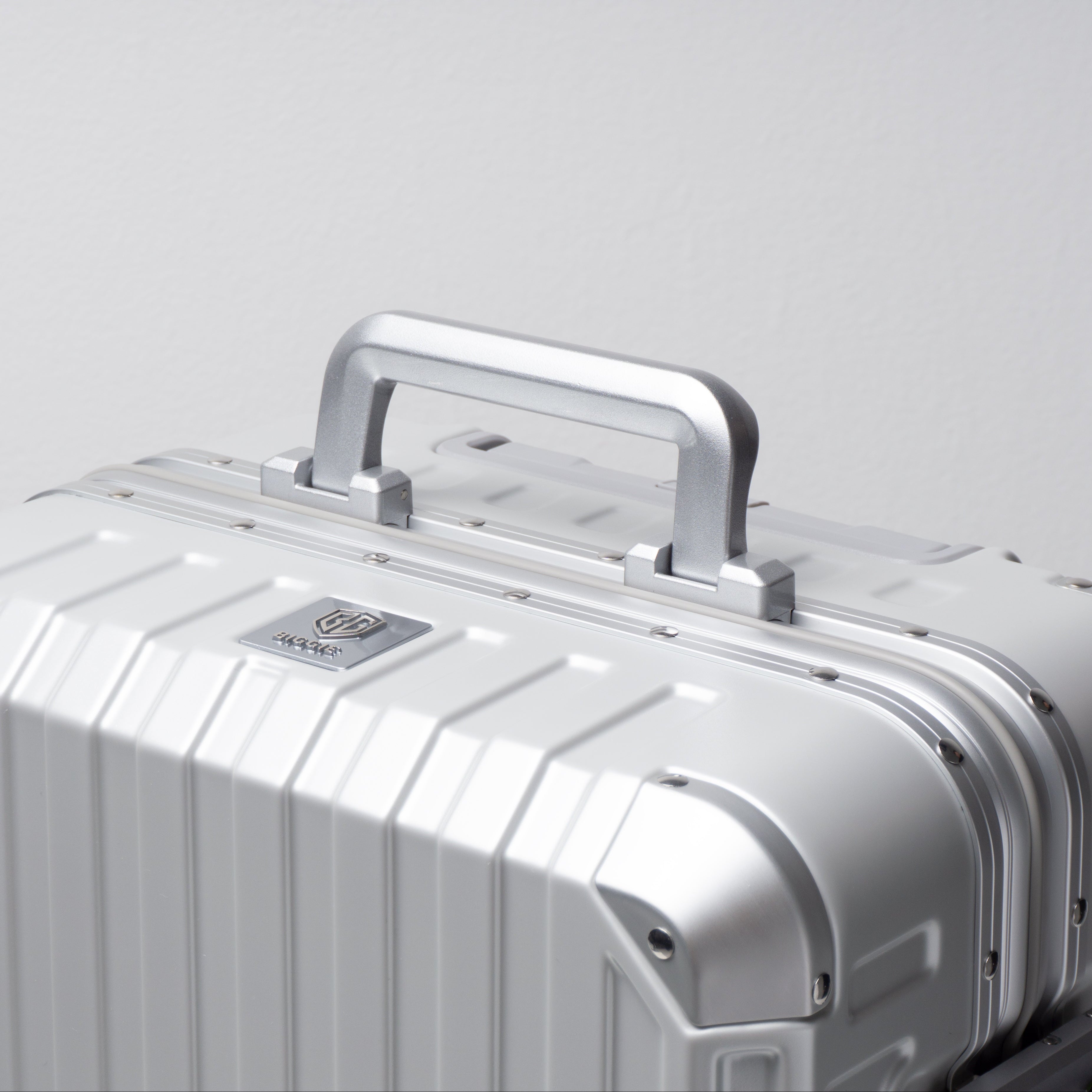Silver suitcase with handle on a light gray background